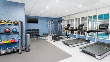 A gym with treadmills, dumbbells, and kettlebells.