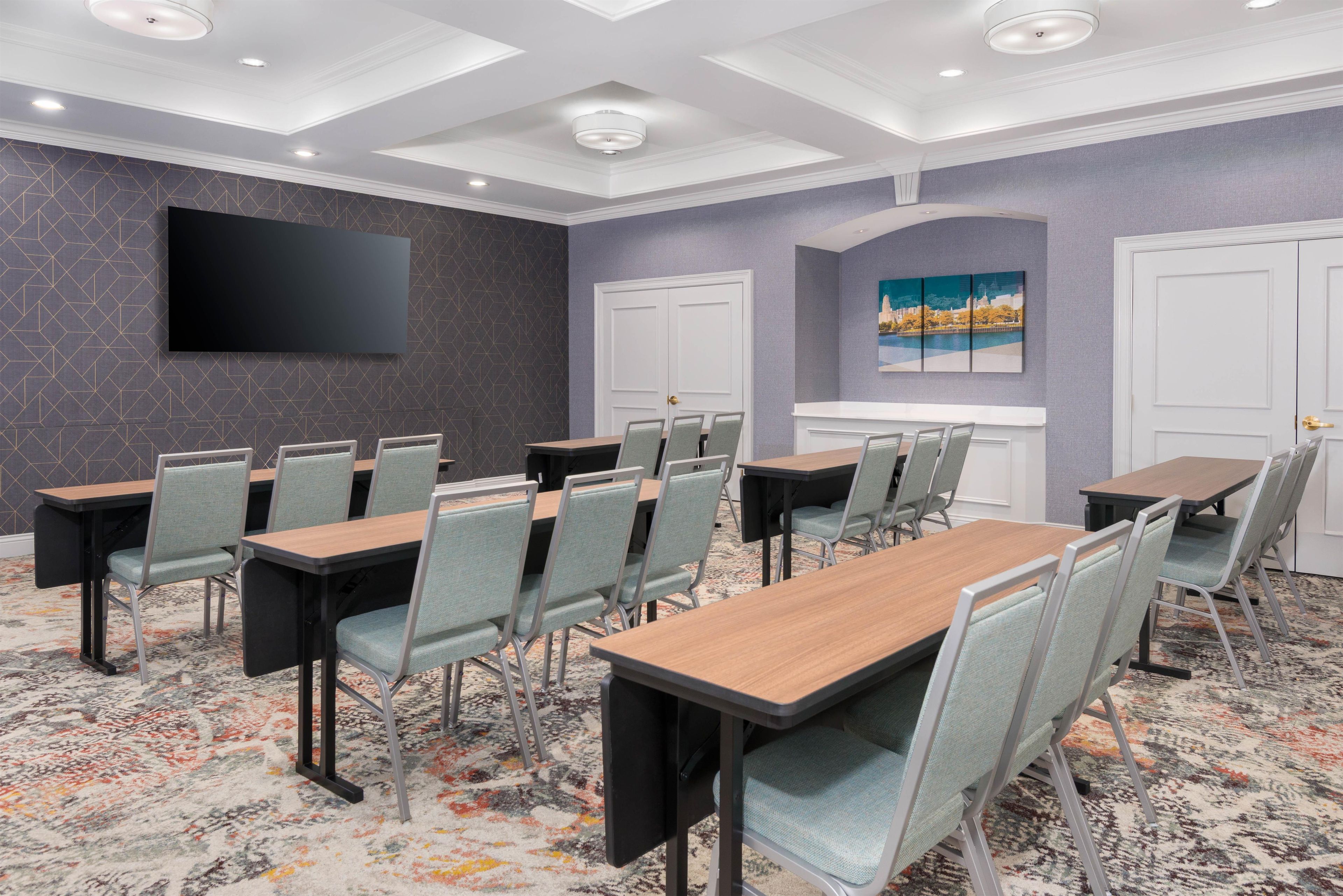 A conference room with a flat-screen TV, multiple tables, and chairs.