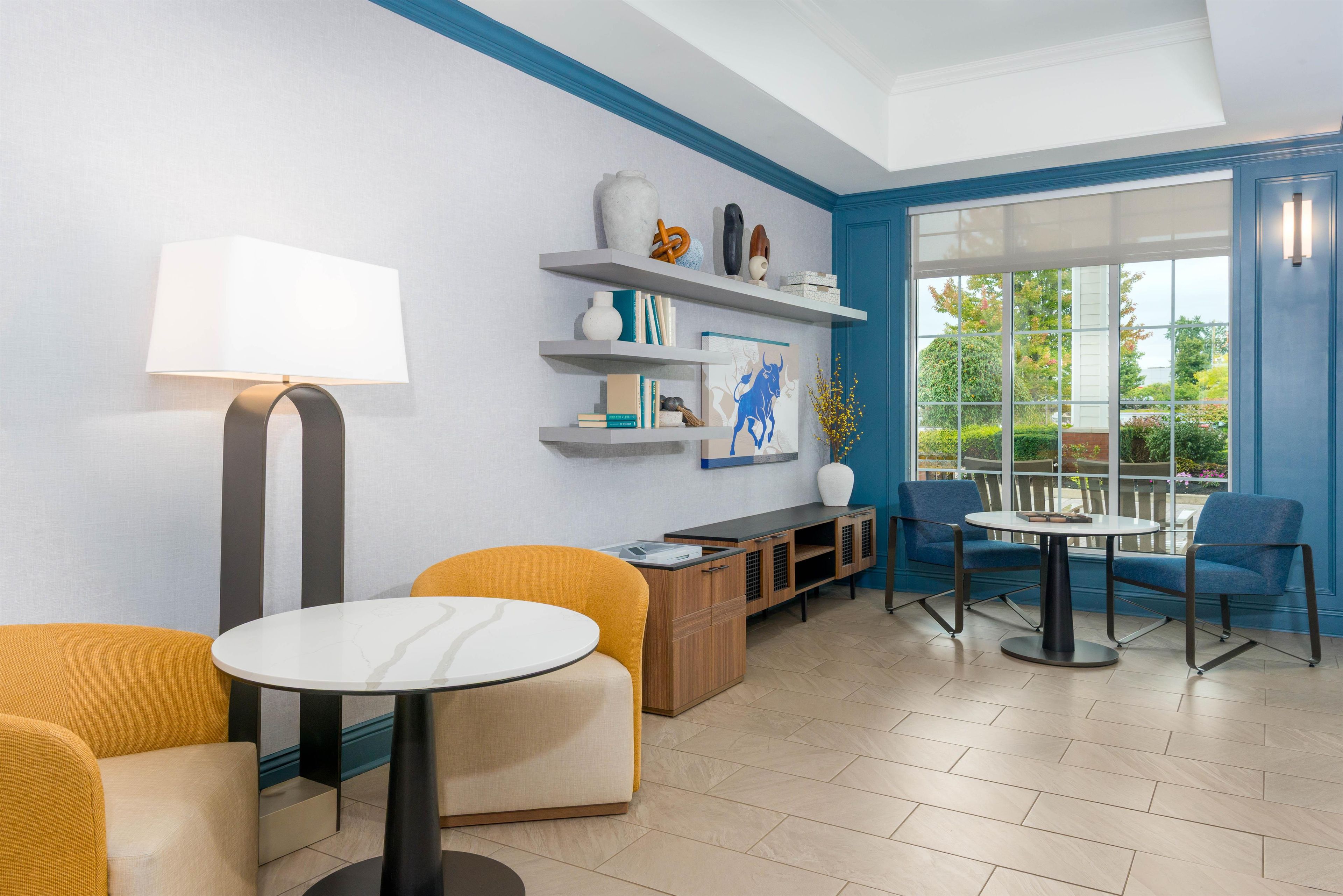 Un área de estar moderna con asientos, una mesa y una estantería con objetos decorativos.
