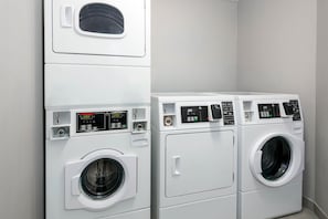 Une buanderie équipée de deux machines à laver superposées et d’un sèche-linge.