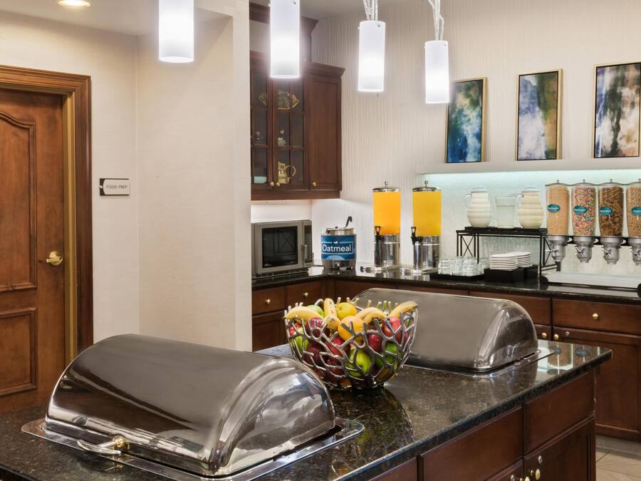 A kitchen area with a buffet setup, including a fruit bowl, a toaster, and a coffee station.