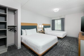 Habitación de hotel con dos camas, un armario, un escritorio y una televisión.
