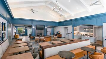 A spacious hotel lobby with multiple seating areas, a bar, and a kitchen visible in the background.