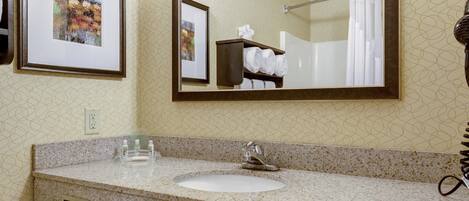 A bathroom with a granite countertop, a sink, a mirror, and a towel rack with towels.
