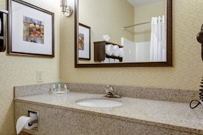 A bathroom with a granite countertop, a sink, a mirror, and a towel rack with towels.