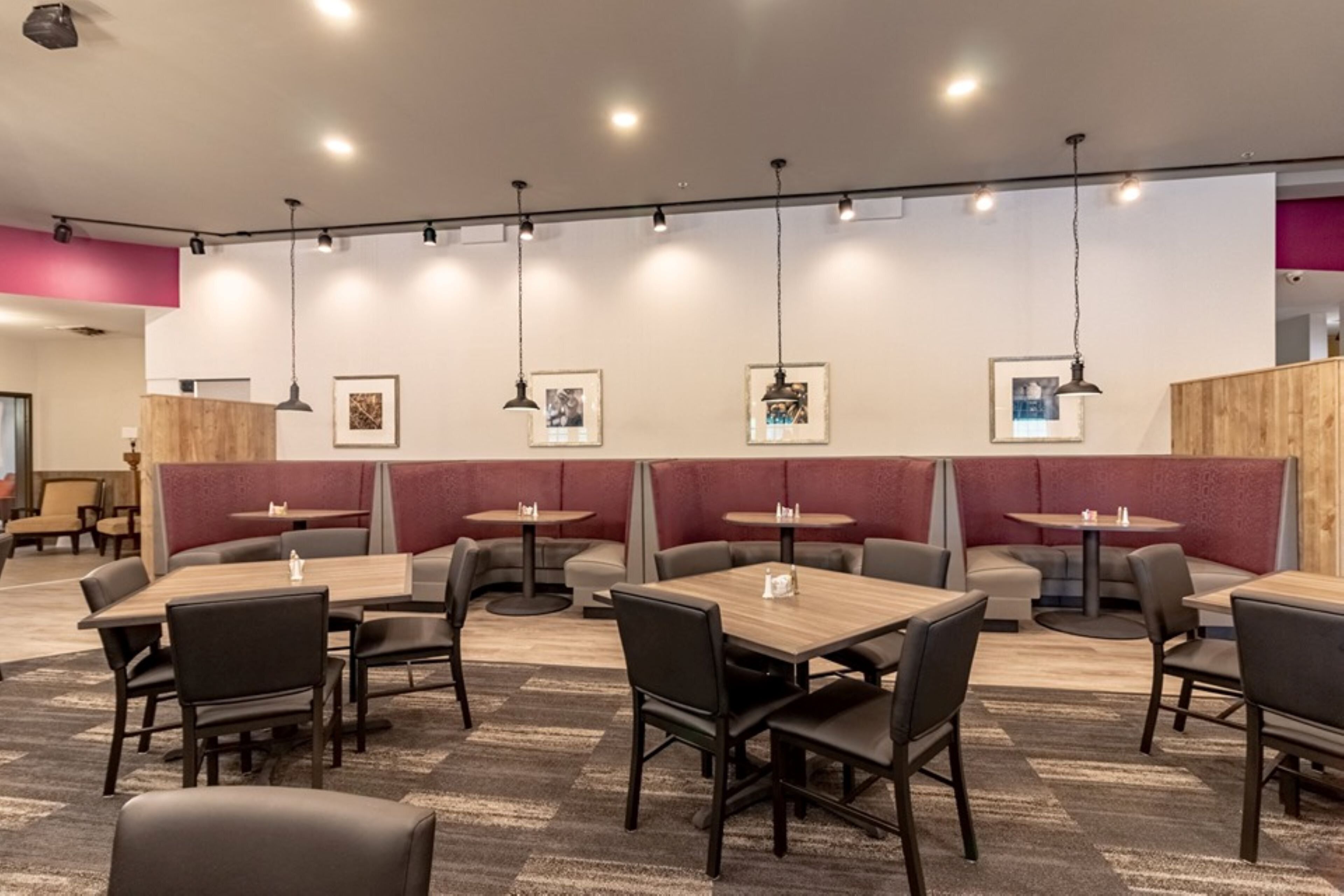 A restaurant interior with booths, tables, and hanging pendant lights.