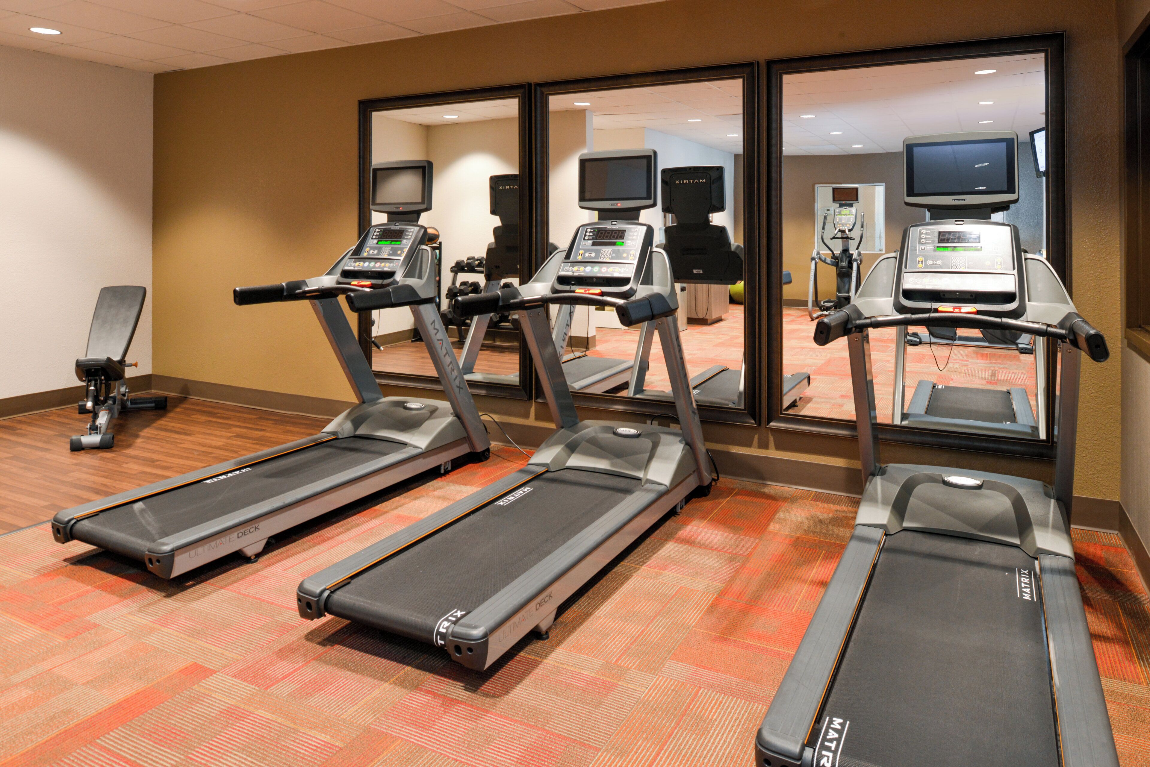 A fitness room with treadmills, exercise bikes, and a mirrored wall.