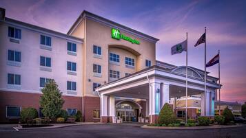 A Holiday Inn hotel with a covered entrance, multiple windows, and flags.