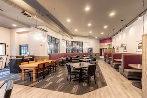 A modern restaurant with high ceilings, pendant lighting, and a mix of booth and table seating.