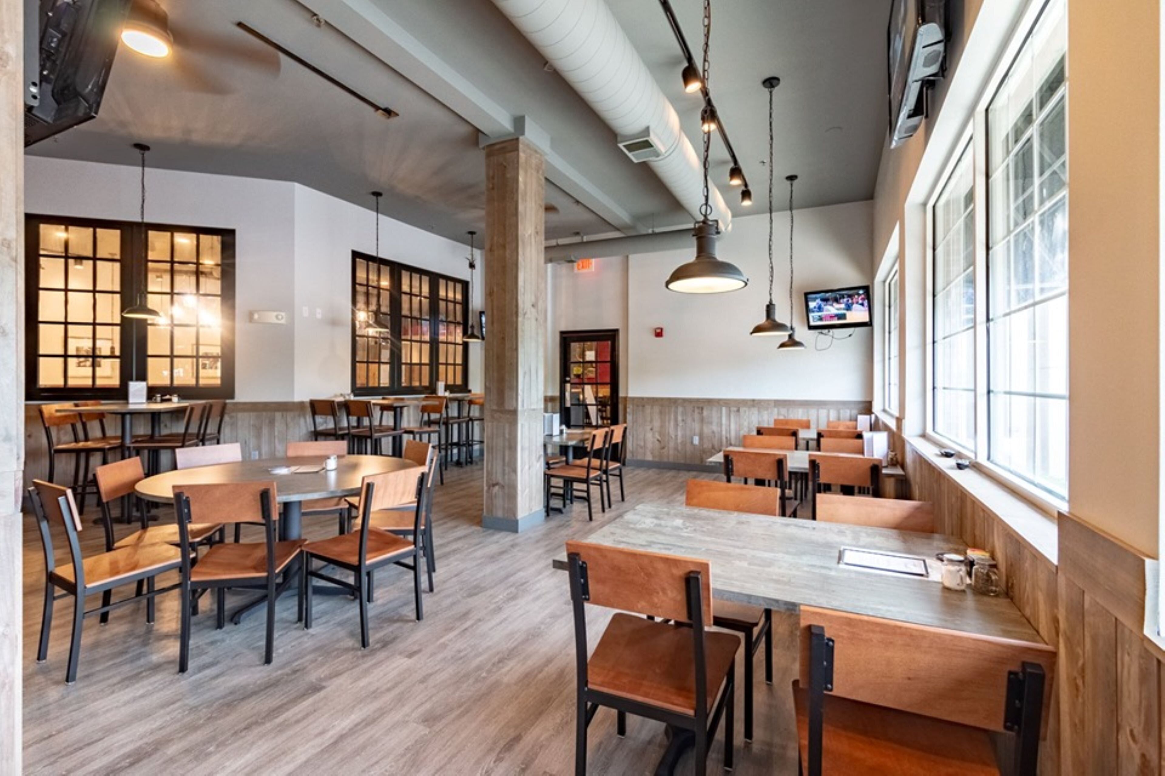 A spacious cafe with multiple seating areas, including tables and booths, and a television mounted on the wall.