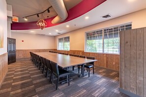 Un salón de conferencias con una mesa larga, sillas y un ventanal grande.