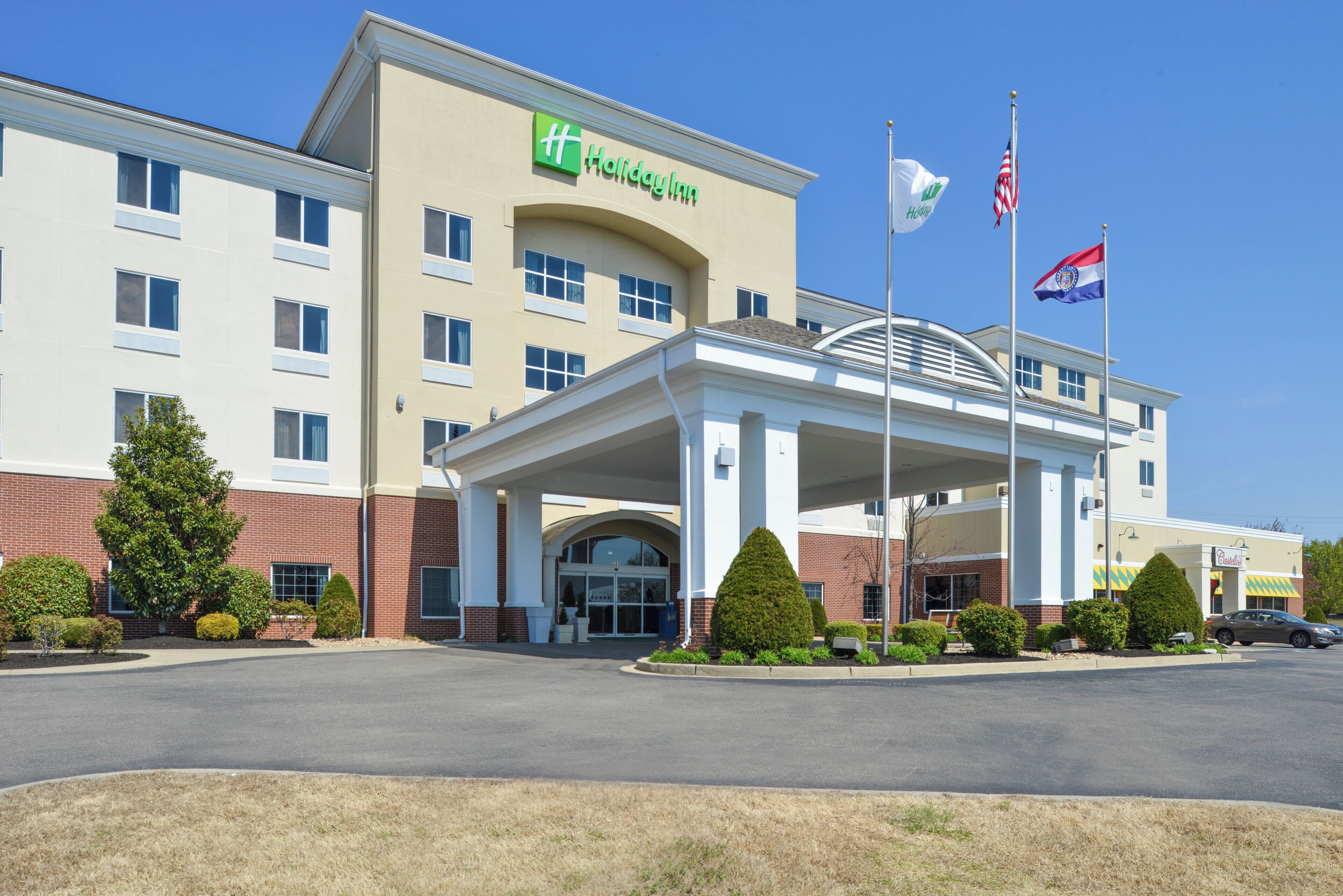 A Holiday Inn Express building with a covered entrance, multiple windows, and a flagpole with flags.