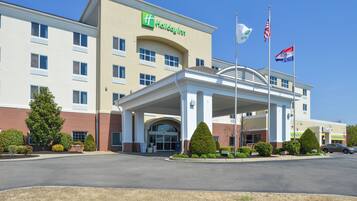 A Holiday Inn Express building with a covered entrance, multiple windows, and a flagpole with flags.