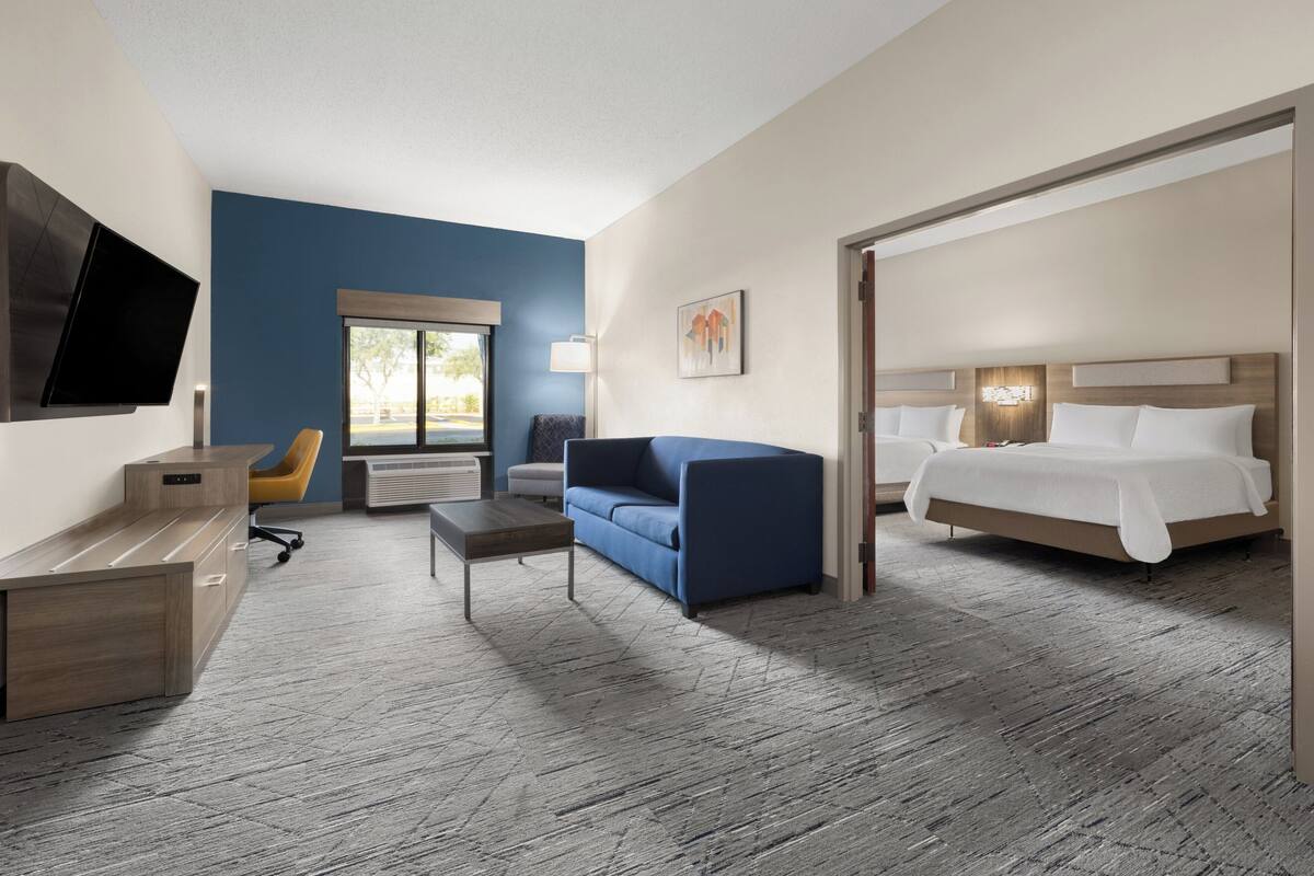 Ein Hotelzimmer mit Bett, Sofa, Schreibtisch, Fernseher und Fenster.