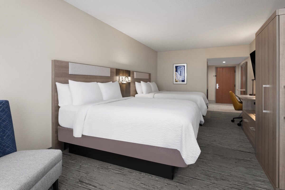 Een hotelkamer met twee bedden, een bureau, een stoel en een kledingkast.
