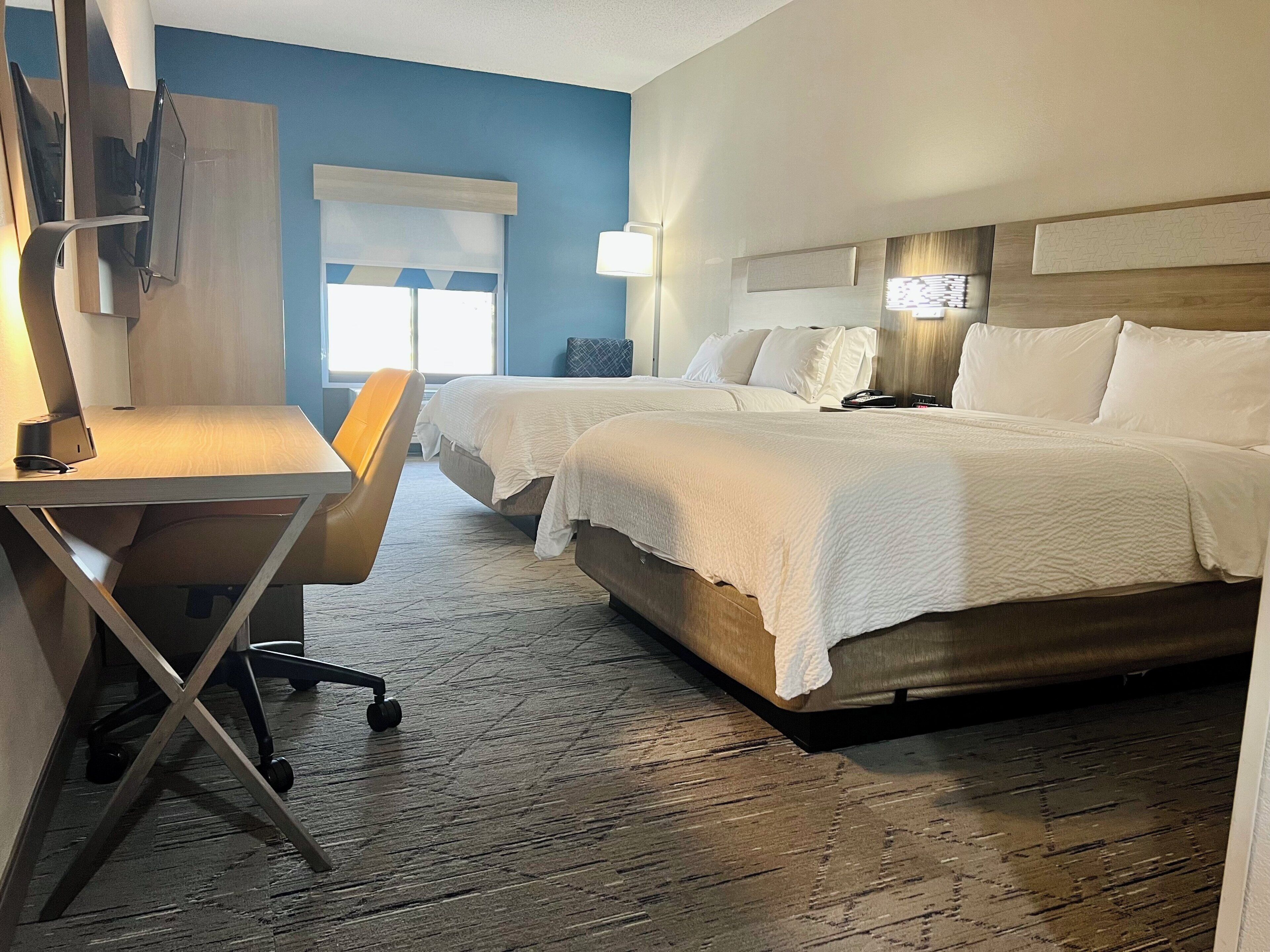 Une chambre d’hôtel avec deux lits, un bureau et une chaise.