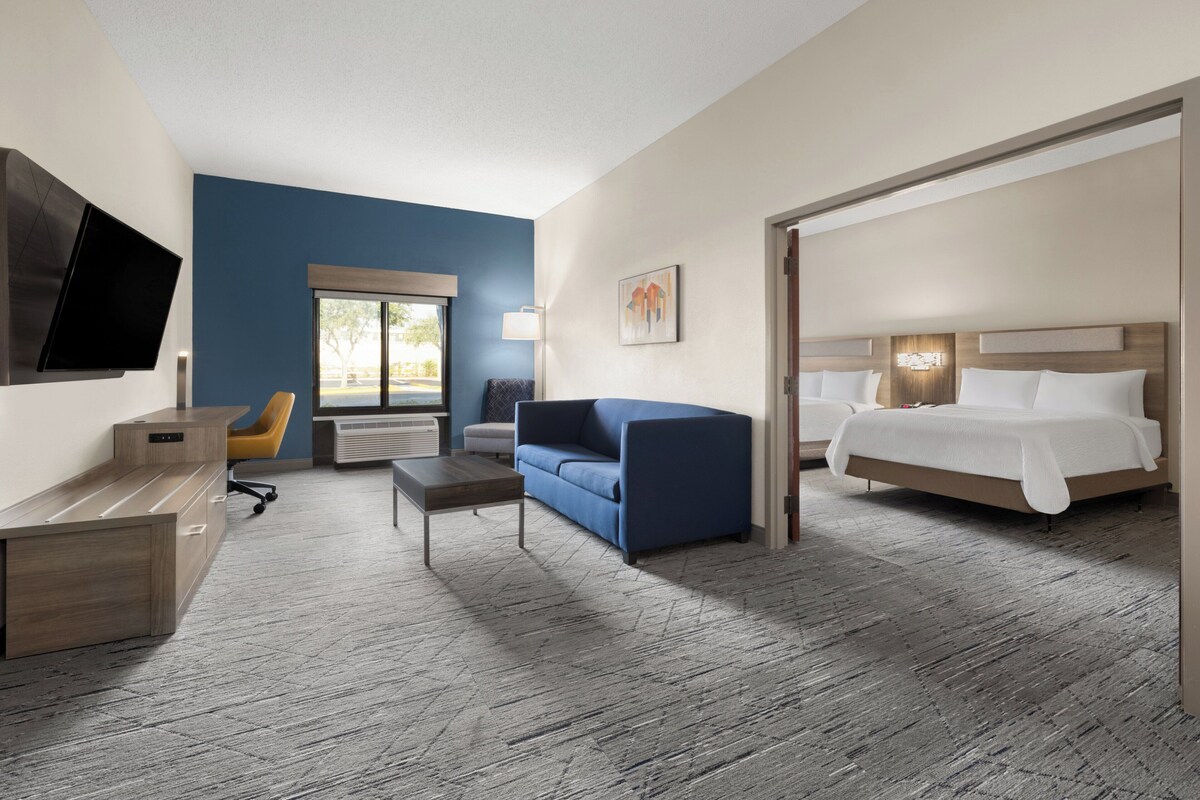 Een hotelkamer met een bed, een bank, een bureau, een televisie en een raam.
