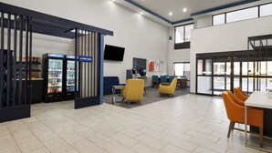 A modern indoor space with a seating area, a coffee station, and a large window providing natural light.