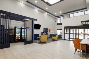 Un espacio interior moderno con zona de estar, estación de café y un amplio ventanal que proporciona luz natural.