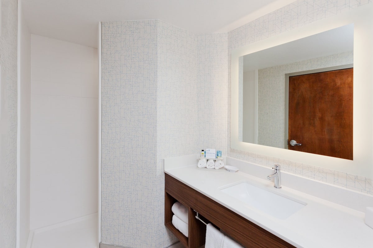 Een moderne badkamer met een witte wastafel, een houten opbergmeubel en een grote spiegel.