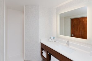 Une salle de bain moderne avec un lavabo blanc, un meuble-lavabo en bois et un grand miroir.