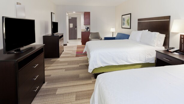 Habitación de hotel con dos camas, televisión, escritorio y baño a la vista.