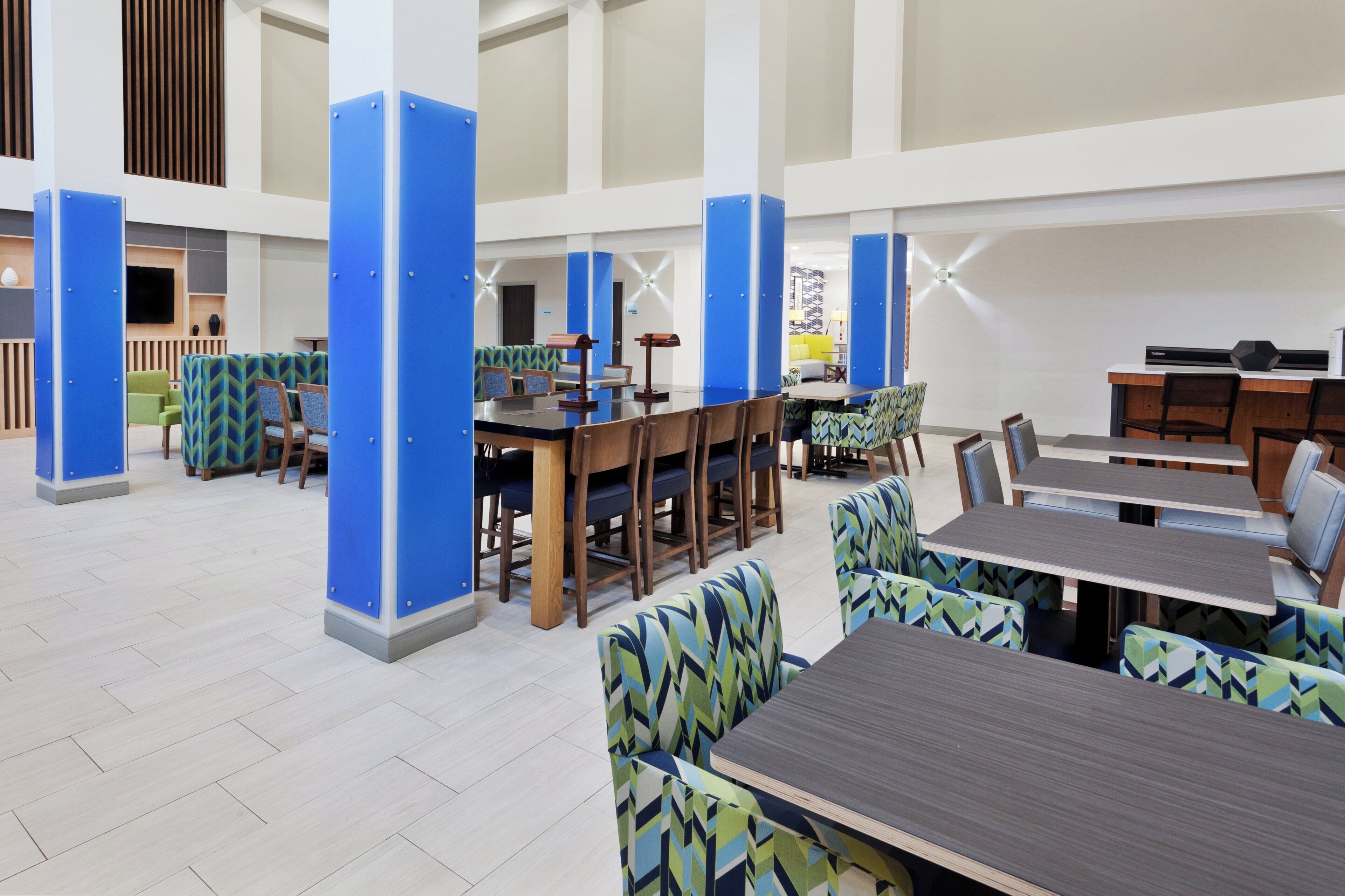 A spacious indoor area with multiple seating arrangements, including tables and chairs, and a large pillar structure.