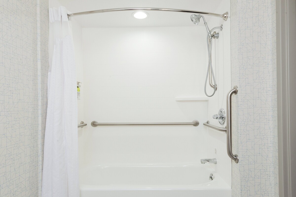 Une douche à l’italienne équipée d’une barre d’appui, d’un pommeau de douche amovible et d’un robinet amovible.