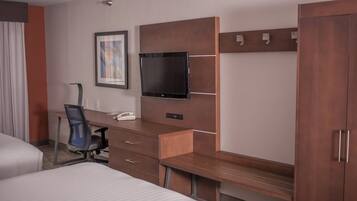 Una habitación de hotel con una cama, un escritorio con una silla, un televisor y un armario.