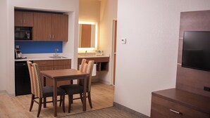 A compact kitchen with wooden cabinets, a microwave, and a sink. There is a dining area with a table and chairs. - Holiday Inn Express Hotel & Suites by IHG (Logan)