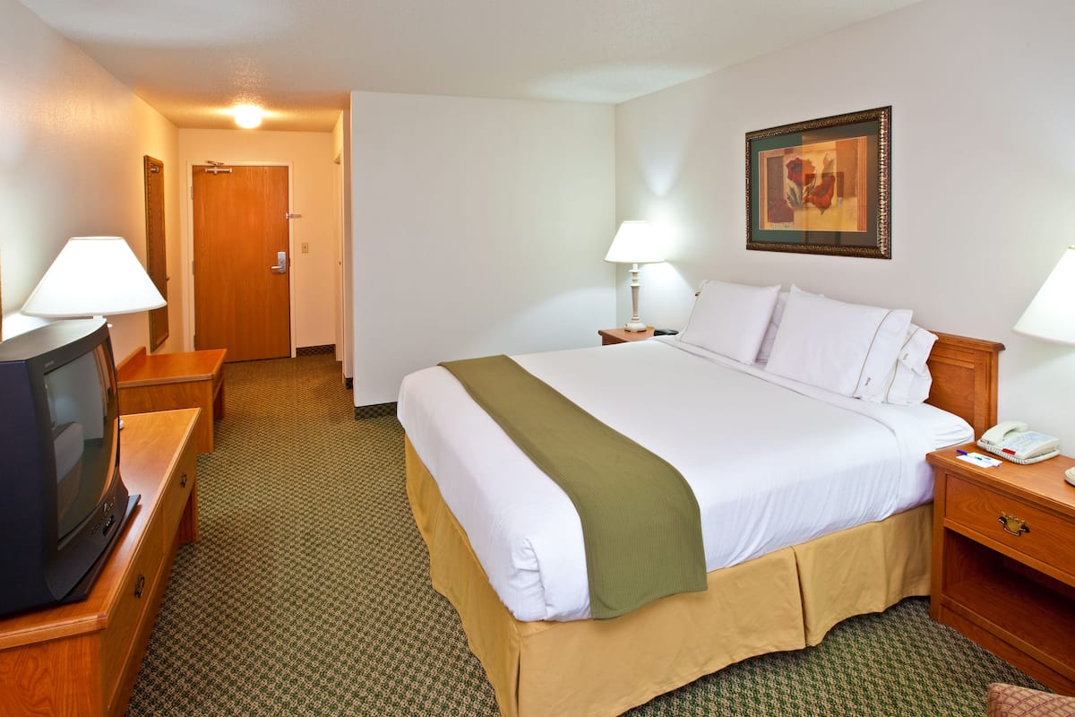 A hotel room with a bed, a TV, a desk, and a lamp.