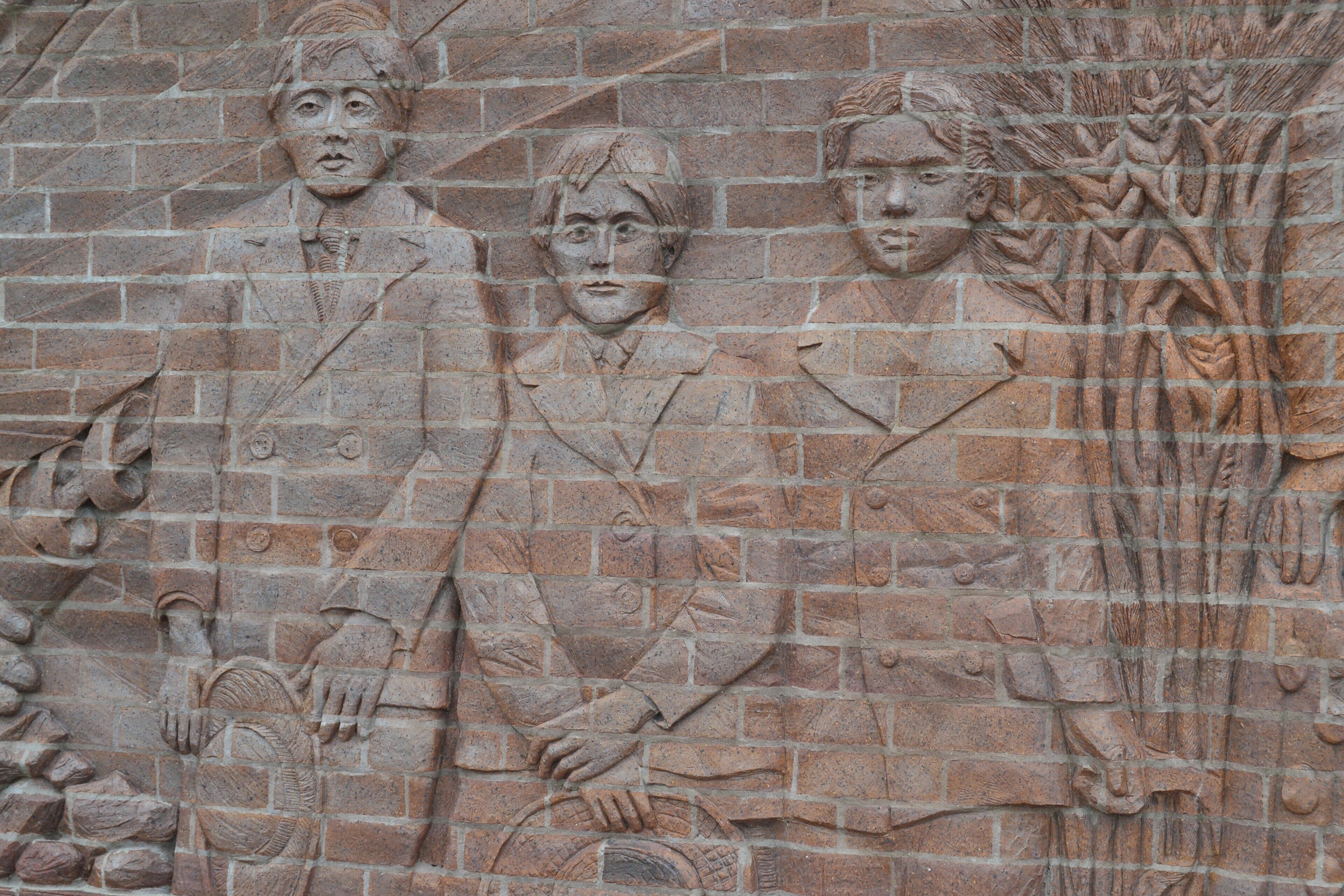 A stone wall with carved figures and symbols, including a figure holding a bow and arrows.