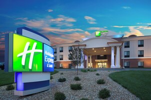 A Holiday Inn Express & Suites hotel with a large illuminated sign, a well-maintained lawn, and a clear sky.