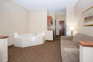 Un baño de hotel con una bañera grande, un lavamanos, un espejo y un perchero para toallas.