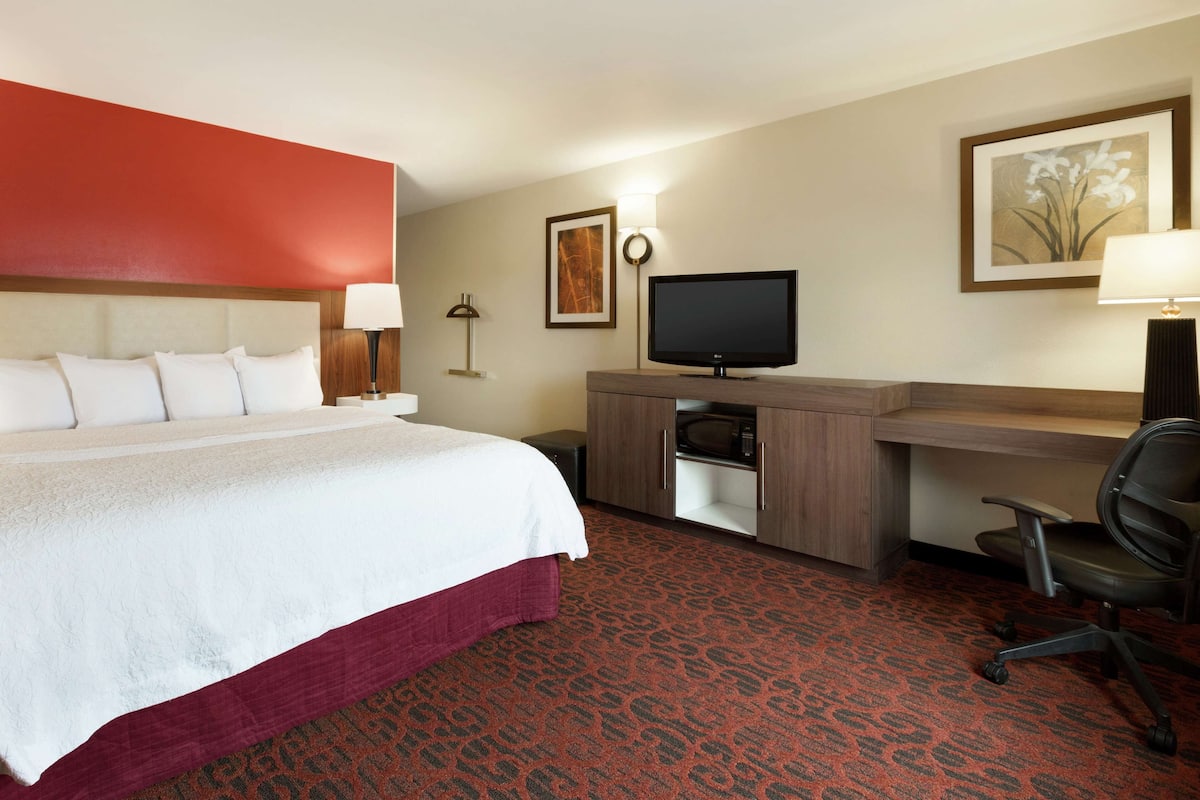 Una habitación de hotel con una cama grande, un escritorio con ordenador, una silla y un televisor.