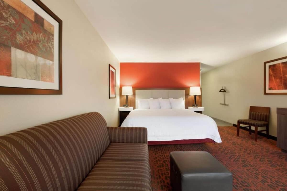 Una habitación de hotel con cama, sofá, sillón y una mesita.