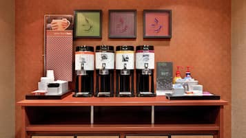 Een koffiehoek met meerdere koffie-apparaten, een menubord en een lijst in een kader aan de muur.