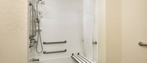 A walk-in shower with a bathtub, grab bars, and a showerhead.