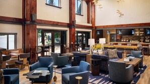A spacious lobby with high ceilings, large windows, and a bar area.