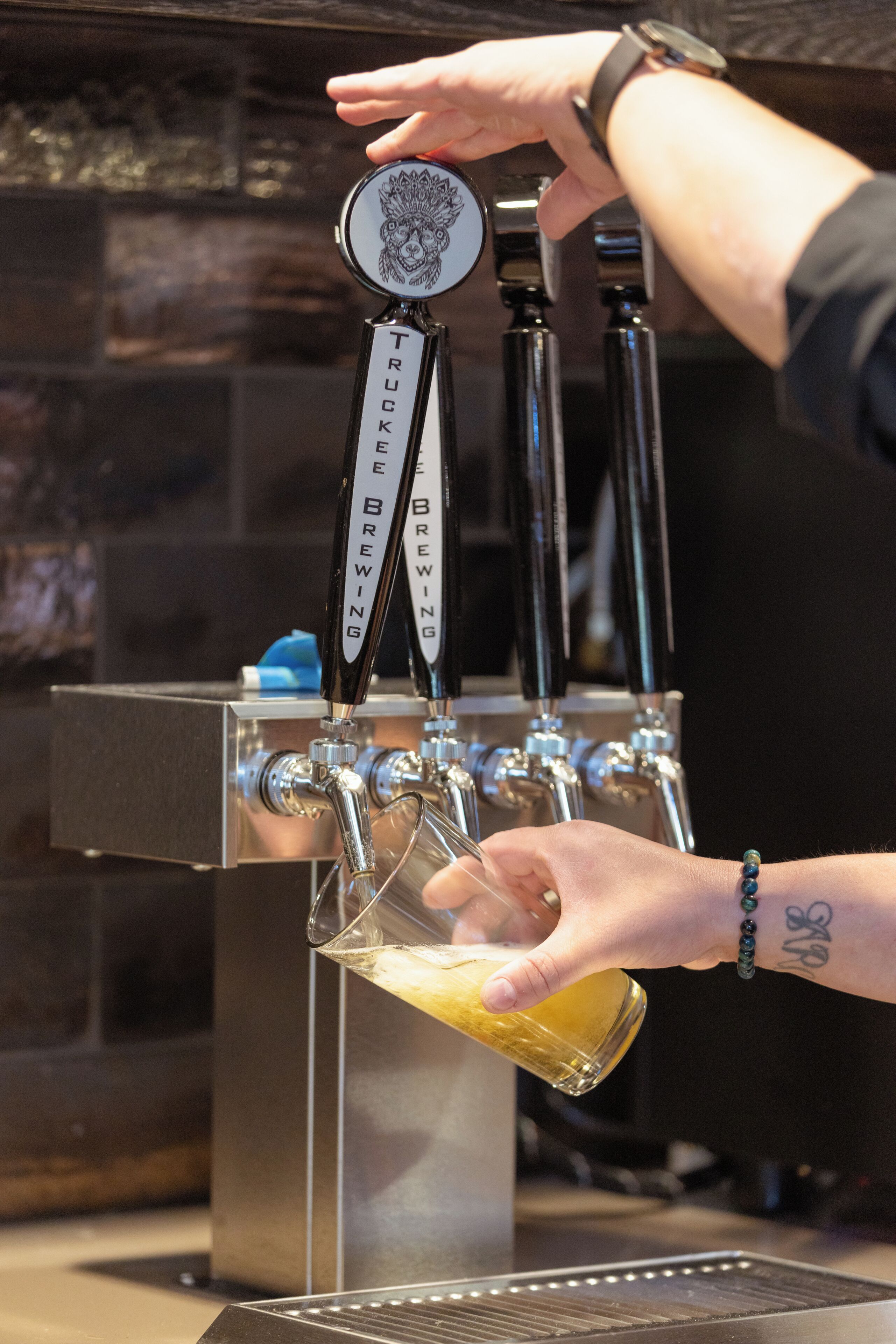 Een hand giet een drankje uit een kraan met de tekst 'Truckee Brewing'.
