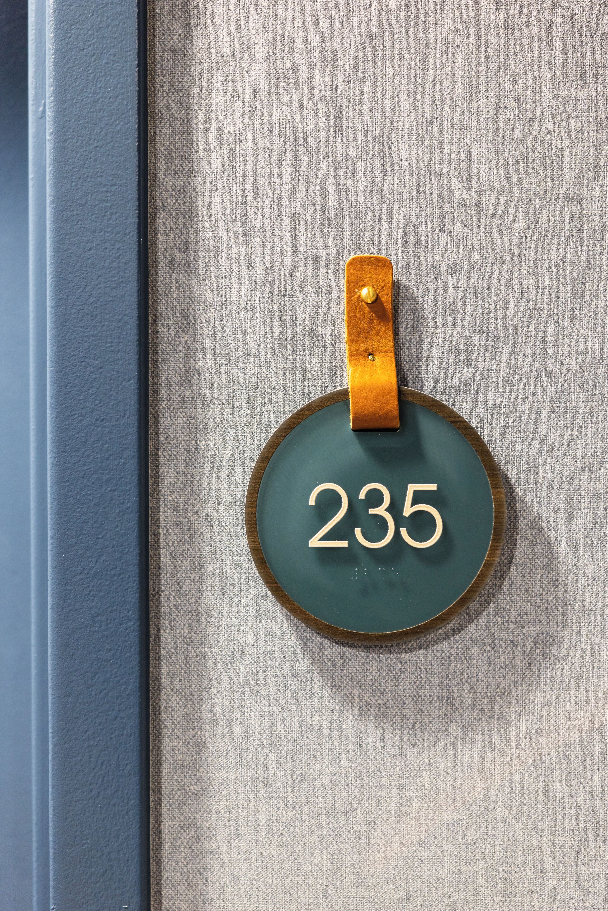 A circular address sign with the number 235 on a textured wall.