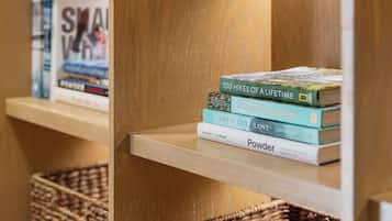 A wooden bookshelf with a stack of books and two woven baskets.