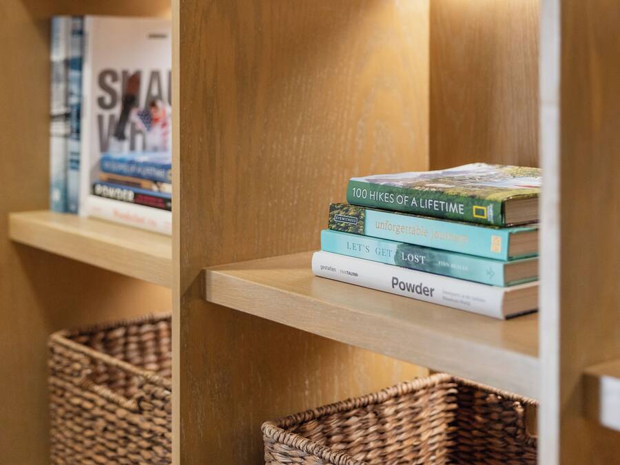A wooden bookshelf with a stack of books and two woven baskets.