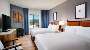 A hotel room with two beds, a TV, a fireplace, and a view of the outdoors.