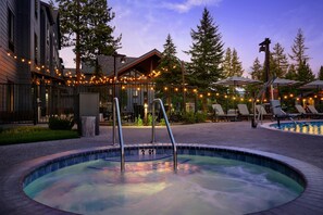 A hot tub surrounded by lounge chairs and umbrellas, with a pool in the background. - Martis Valley Lodge, Tapestry Collection by Hilton (Truckee)