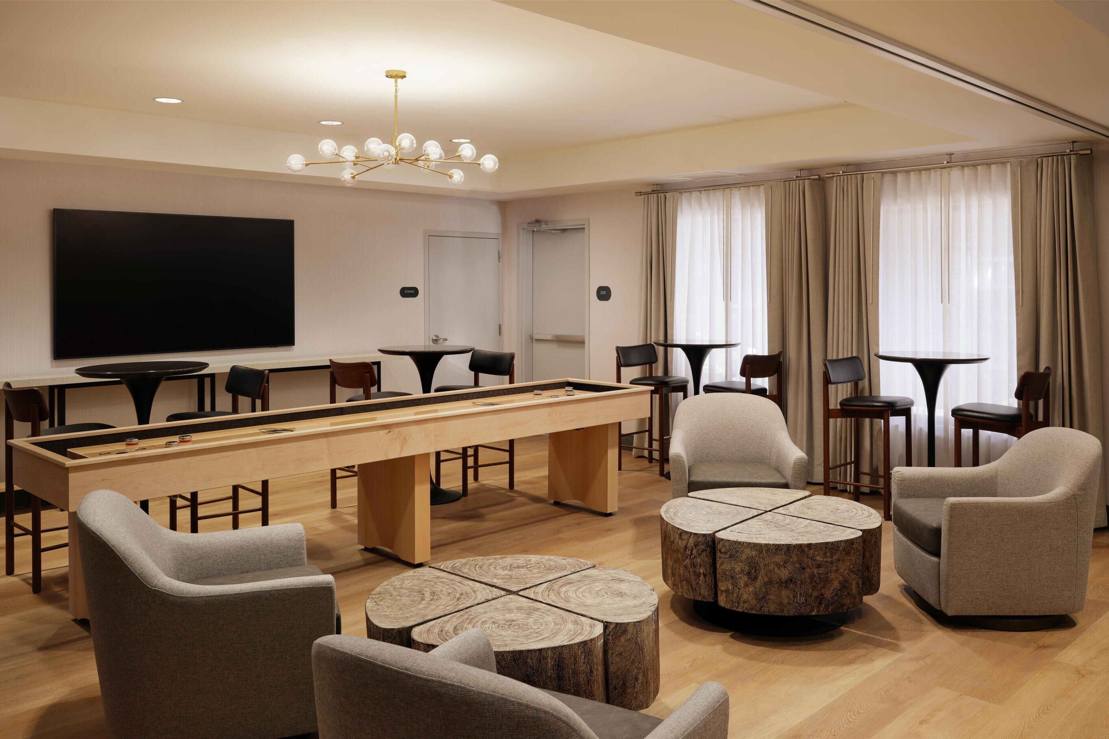A modern lounge area with a pool table, comfortable seating, and a large flat-screen TV.