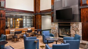 A spacious lounge area with a stone fireplace, comfortable seating, and a large flat-screen TV mounted on the wall.