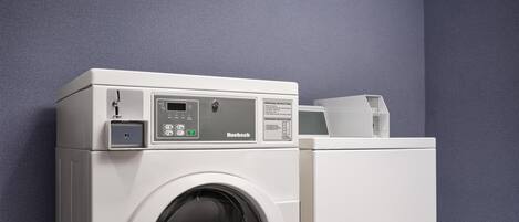 Eine frontgeladene, weiße Waschmaschine mit Bedienfeld vor einer blauen Wand.