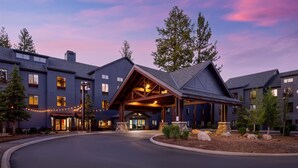 A multi-story hotel with a covered entrance, stone pillars, and a landscaped driveway.