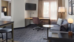 A hotel room with a bed, desk, chair, sofa, TV, lamp, and a small table. - Residence Inn by Marriott Saratoga Springs (Saratoga Springs)